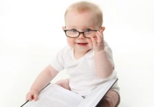 Photo of baby wearing glasses reading a book alone