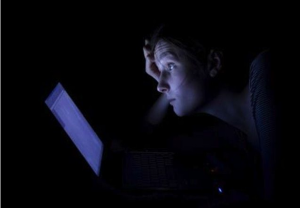Blue light from tablet shining on face of person trying to sleep