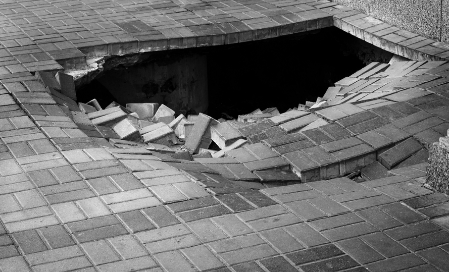 Photo of large hole in a brick sidewalk
